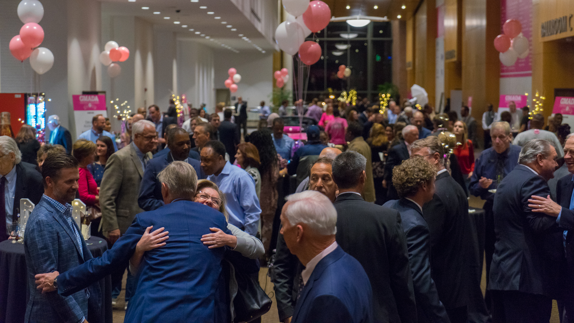  Many people in ballroom with pink balloons 